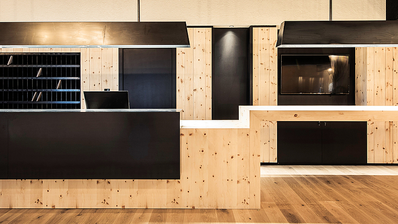 Hotel-Rezeption mit heller Holzverkleidung und schwarzen Einbauelementen und Tresen.