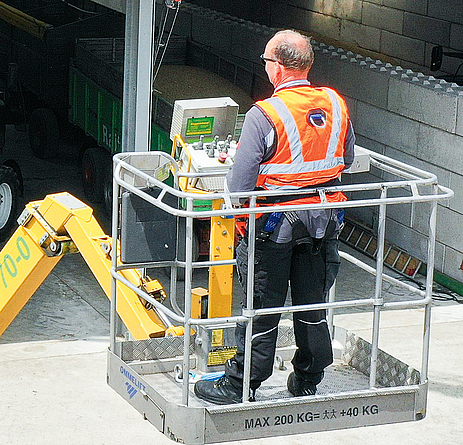 Steuerung des Reinigungskrans für die Reinigung von PV-Anlagen von Hebebühne aus Bild von oben auf eine Bürste, die an einem Ausleger befestigt ist und auf einem Dach die Photovoltaik-Module säubert.