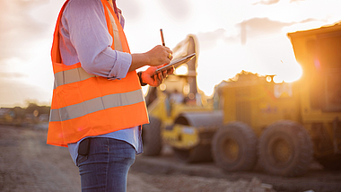 Ein Bauarbeiter benutzt ein Tablet auf einer Baustelle.